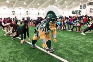 The MSU Spartan mascot exercising with a large group of children