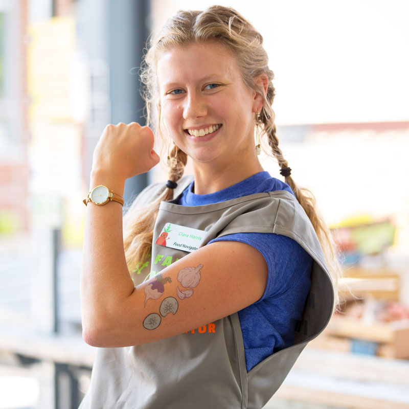 Food Navigator flexes her arm covered with fake vegetable tattoos