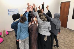 Women in hijabs raising their arms together as a team